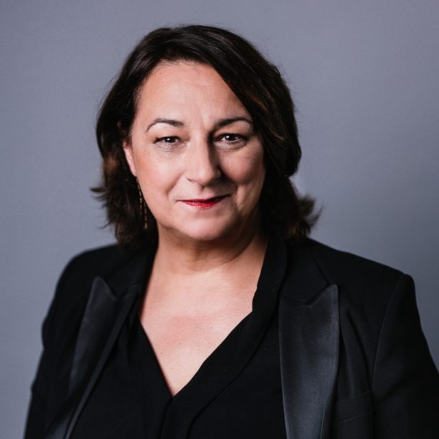 La parfumeuse Sophie Labbé en costume noir et rouge à lèvres rouge.